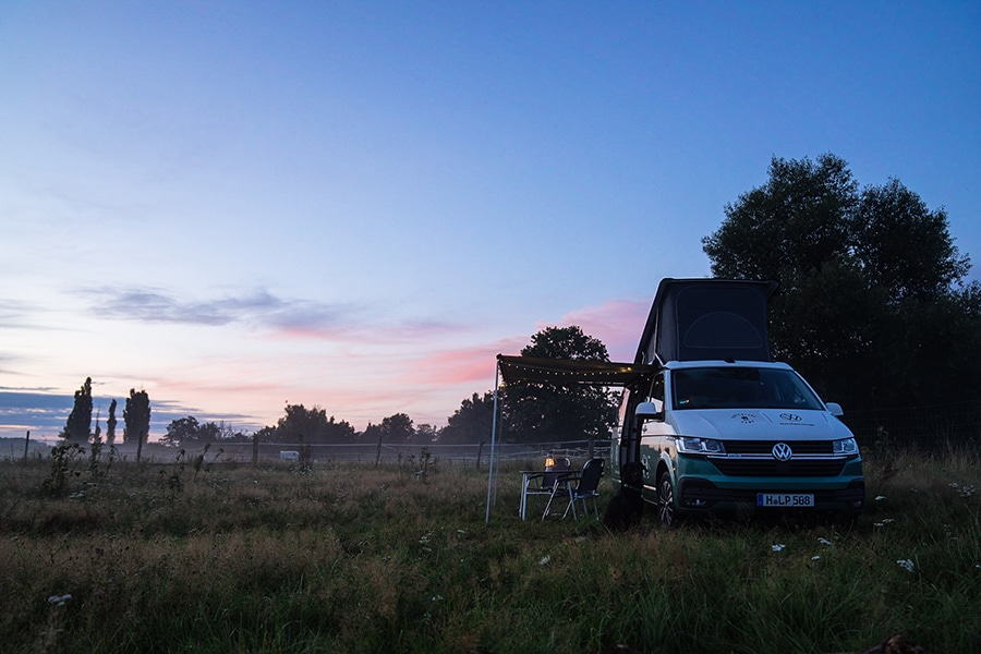 Camper auf Wiese in der Abenddämmerung