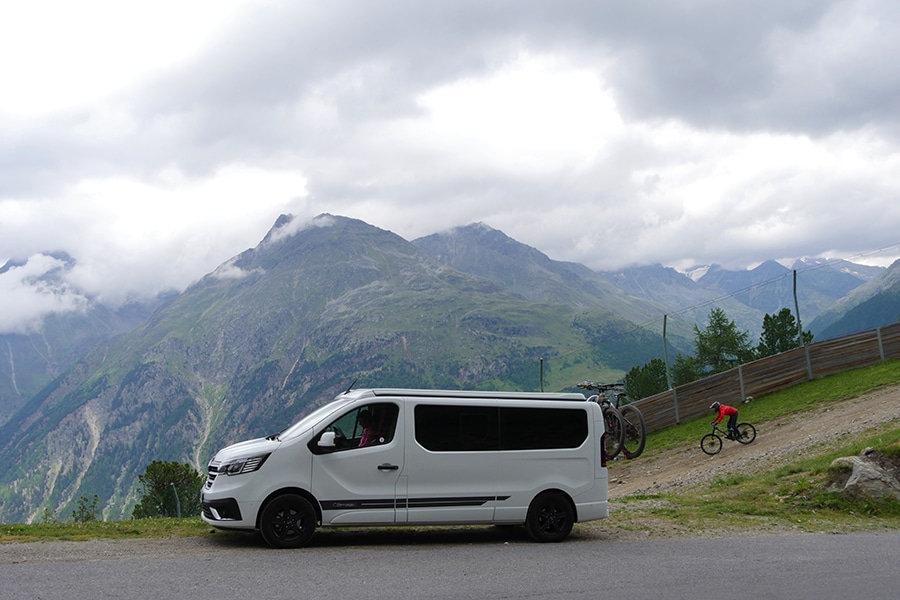 Der Wavecamper Renault Trafic long vor Bergkussise auf einer Straße