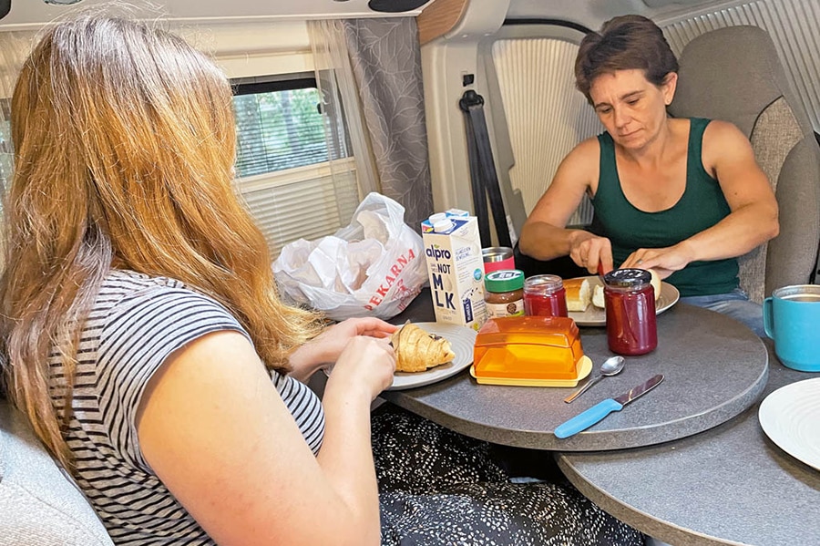 Zwei Camperinnen frühstücken in der Dinette mit erweiterbarem Tisch