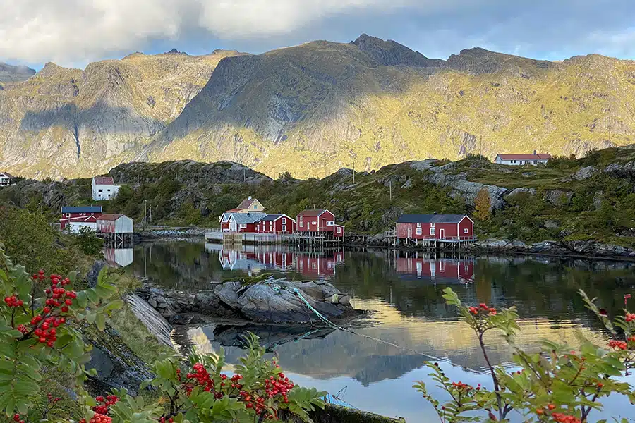 Kleines Dorf mit typisch norwegischen roten Häuschen am Ufer und am Fuß der Berge