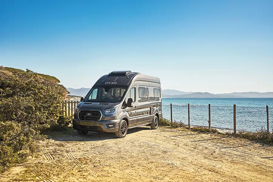 Schwarzes Wohnmobil von Etrusco auf sandigerm Untergrund am Meer