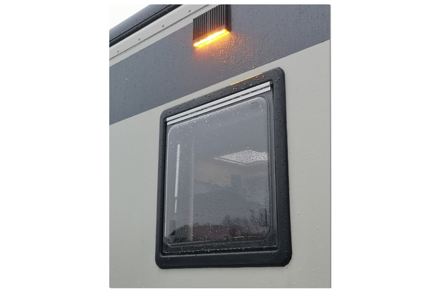 Flache LumiCoin Umfeldleuchte angebracht außen über einem Fenster eines Reisemobils