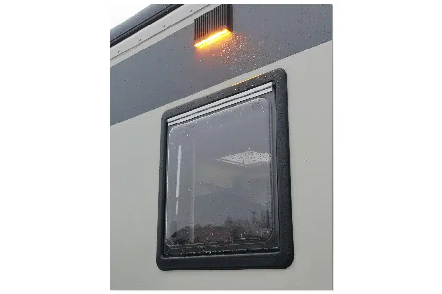 Flache LumiCoin Umfeldleuchte angebracht außen über einem Fenster eines Reisemobils