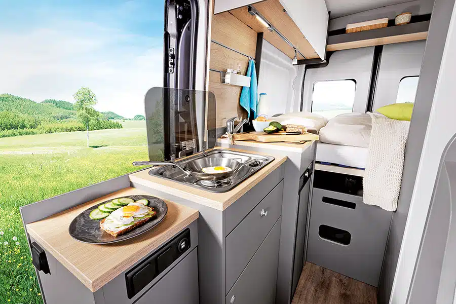 LMC Innovan Ford 590 Küche mit hellgrauen Möbeloberflächen und Holz-Arbeitsplatte.