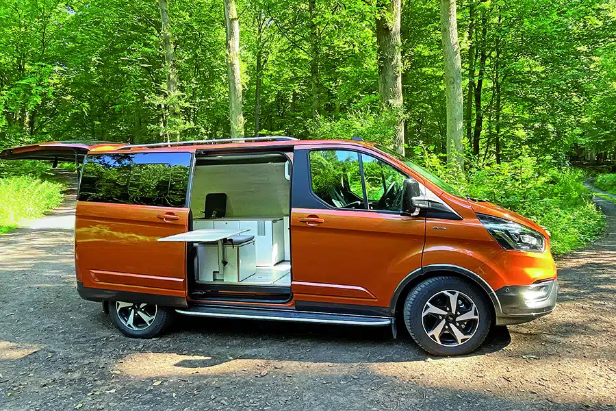 Orangefarbener Campervan Good Life Van auf einem Waldweg