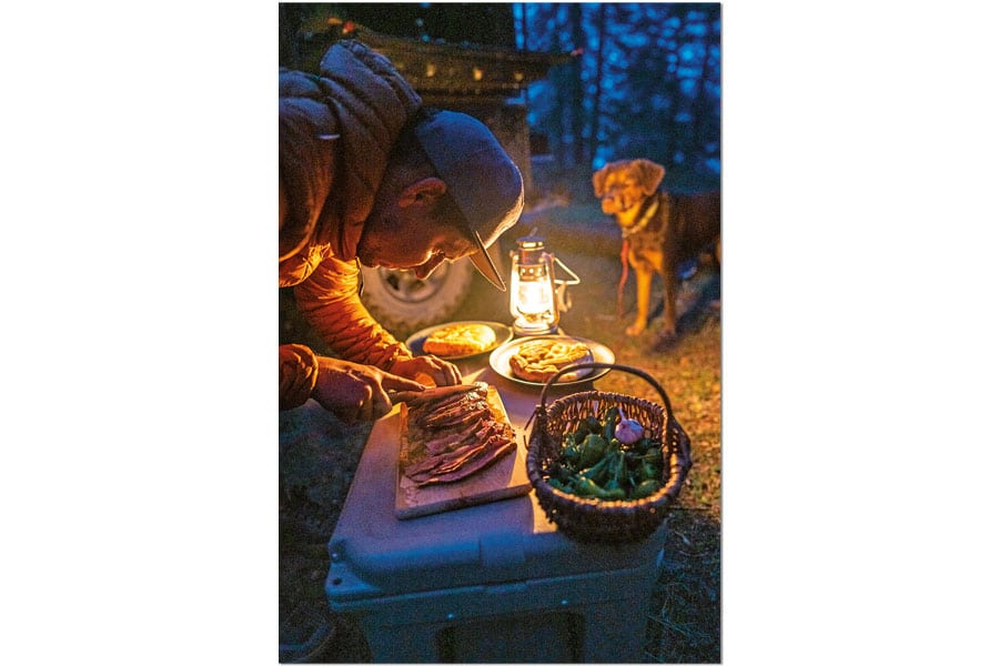 Anrichten einer Mahlzeit draußen im Lampenschein bei Dunkelheit