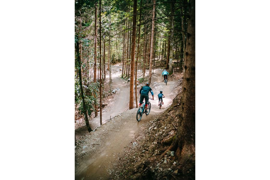 Familie auf hügeligem Waldtrail mit Mountainbikes