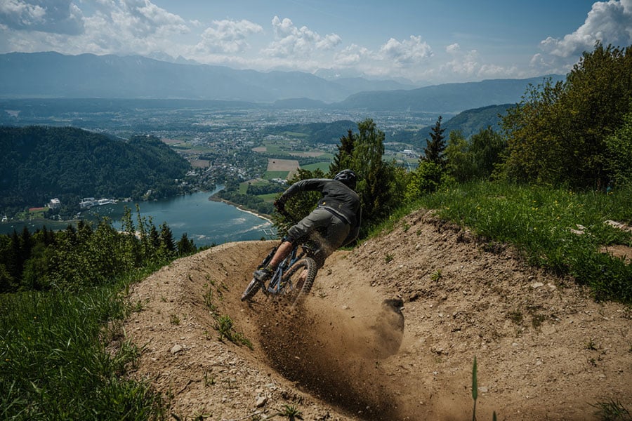 Mountainbiker auf schrägem, sandigem Trail auf Hügelspitze