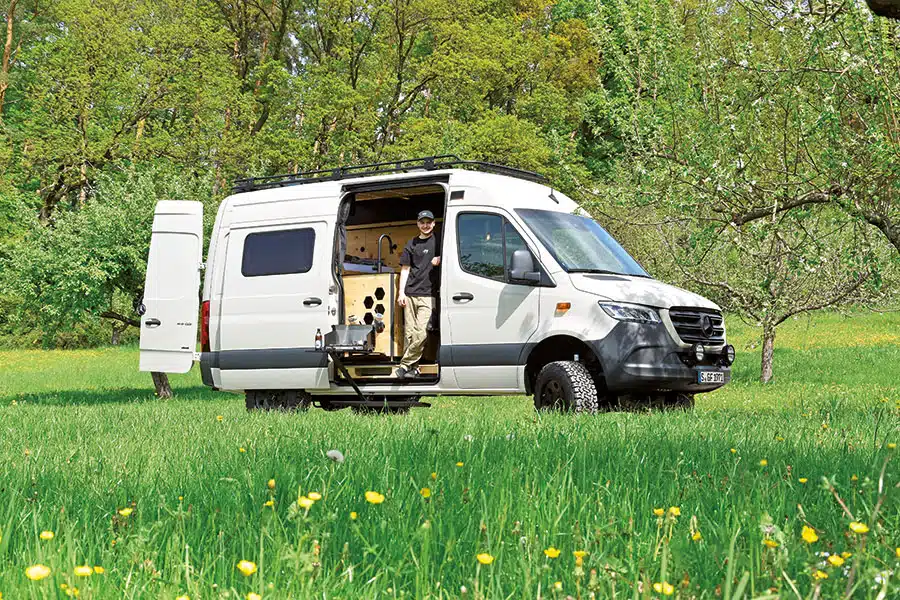 Weißer Sprinter mit Wohnmobilausbau und offener Schiebetür auf Wiese