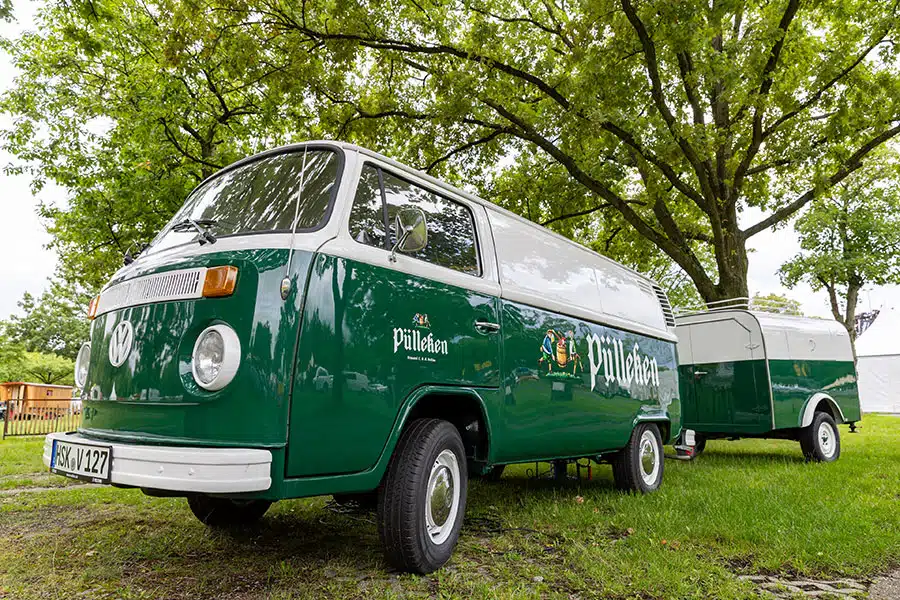 Grün-weißer VW T2 mit Anhänger
