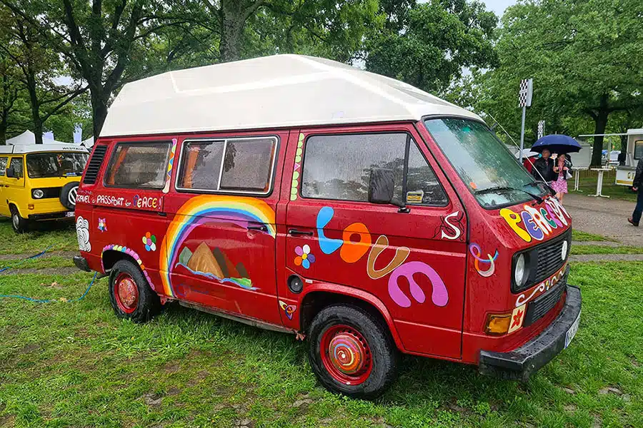 Mit Hippie-Motiven und Schriftzügen bemalter roter VW T3