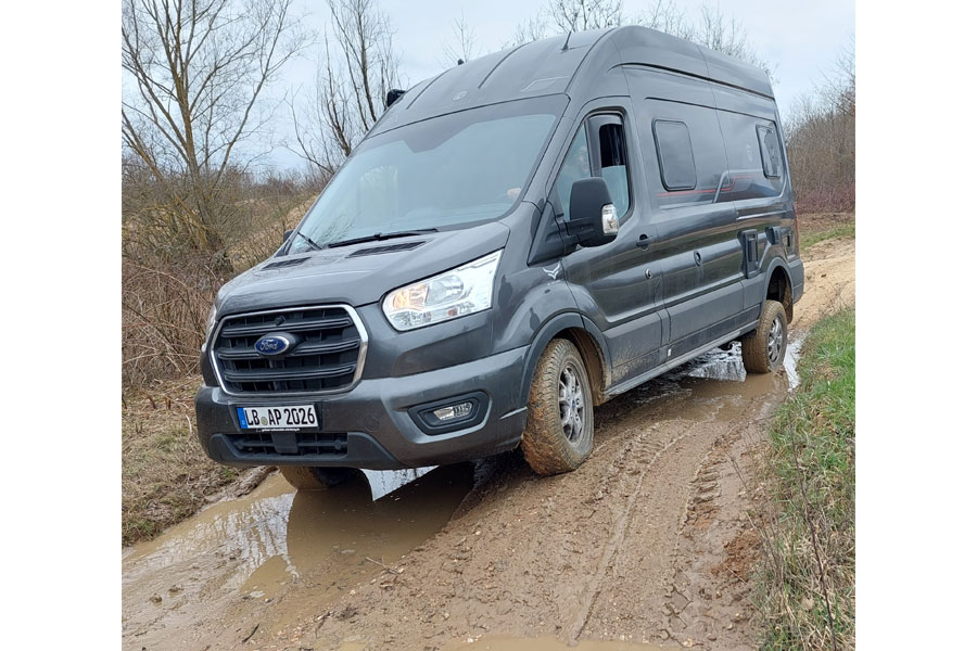 Allrad-Kastenwagen fährt auf unbefestigtem Weg einen Hügel hinab