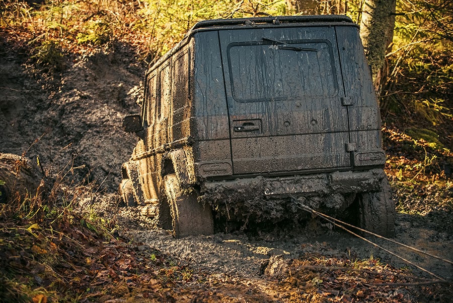 Im tiefen Schlammloch im Wald festgefahrener schmutziger Geländewagen