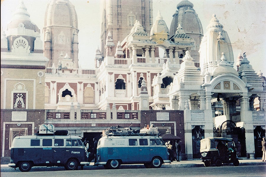Zwei weiß-blaue VW-Busse stehen vor einem großen, hellen und reich verzierten Tempel