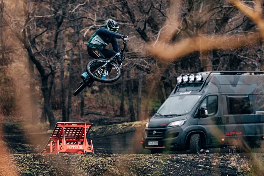Mountainbiker beim Sprung neben dem Sunlight Adventure Concept-Camper