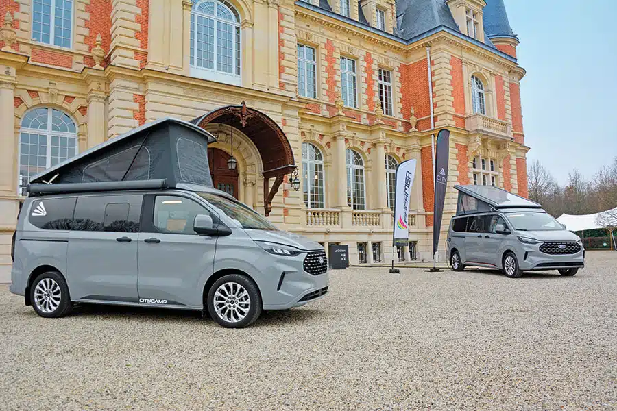 Zwei graue Campingbusse mit Aufstelldach vor altem Schlossgebeäude