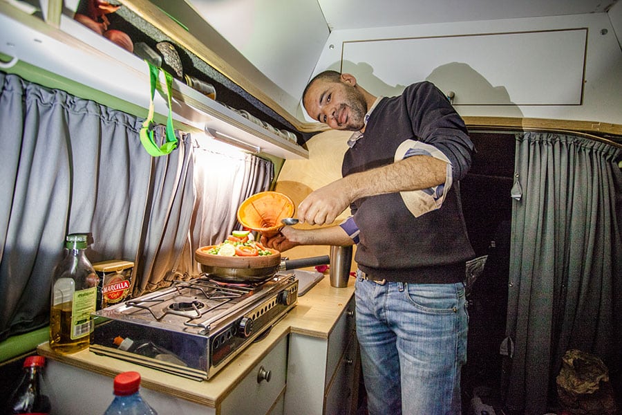 Mann beim Kochen im Campingbuss