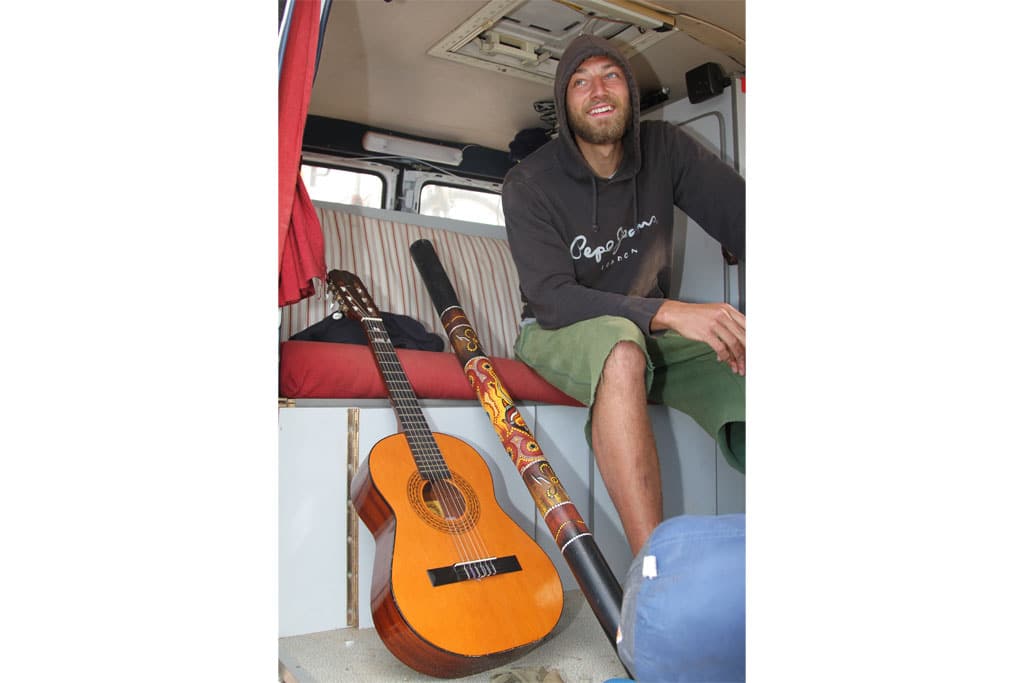 Camper mit Gitarre und Didgeridoo in seinem Fahrzeug