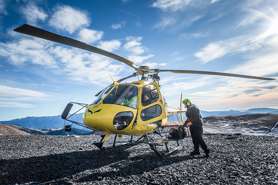 Gelber Helikopter auf Hochplateau im Gebirge