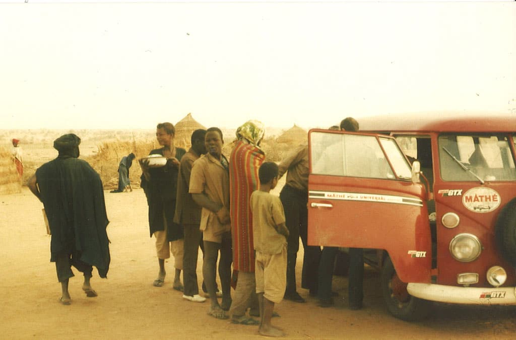 Eine Gruppe Menschen steht neben einem VW Bus in der Wüste