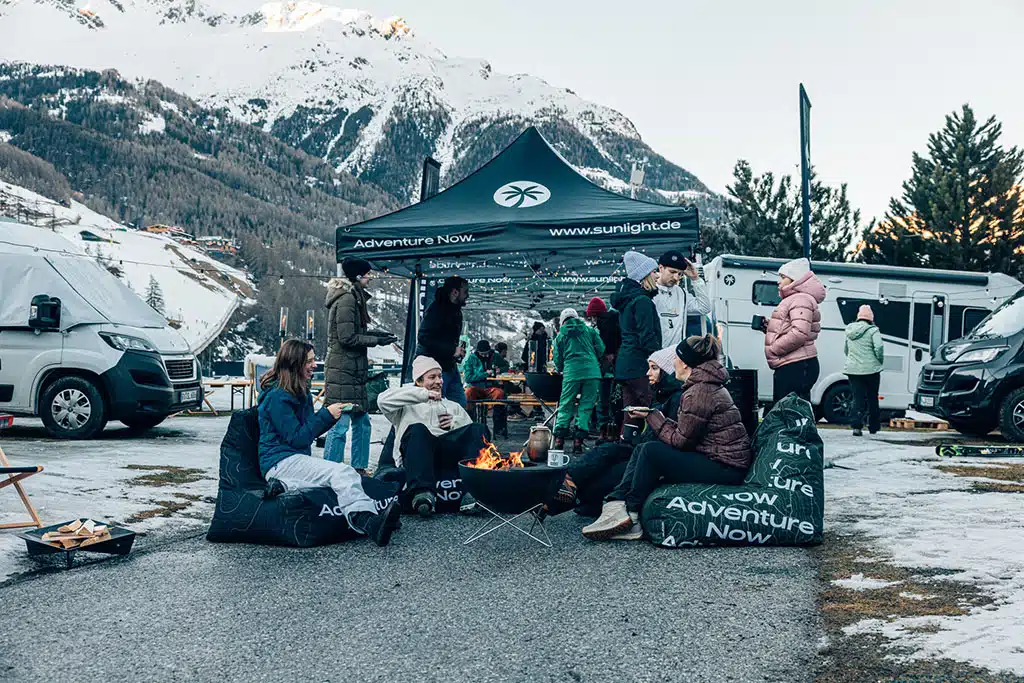 Sunlight Winter Camp and Ride 2024: Eine Gruppe Camper an kleinem Lagerfeuer im Wintercamp in den schneebedeckten Bergen