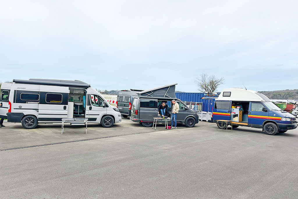 Mehrere Campervans und Camper auf einem asphaltierten Platz