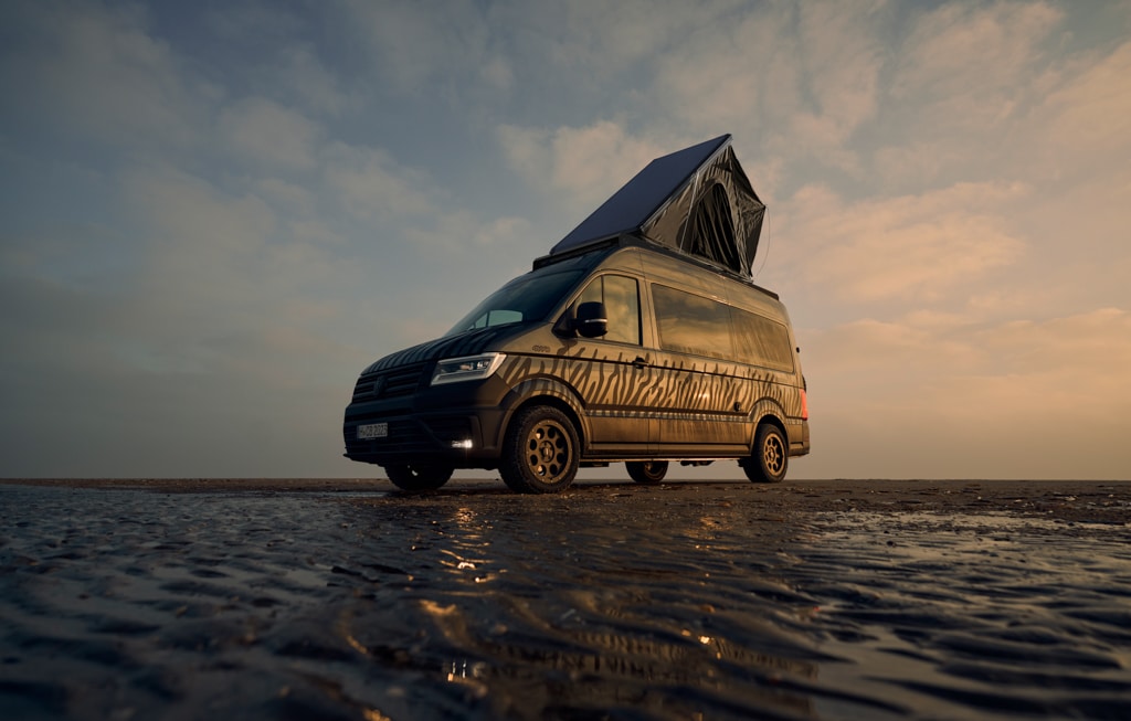 Custom-Bus Camper XL: Kastenwagen mit Aufstelldach am Meer während der Dämmerung