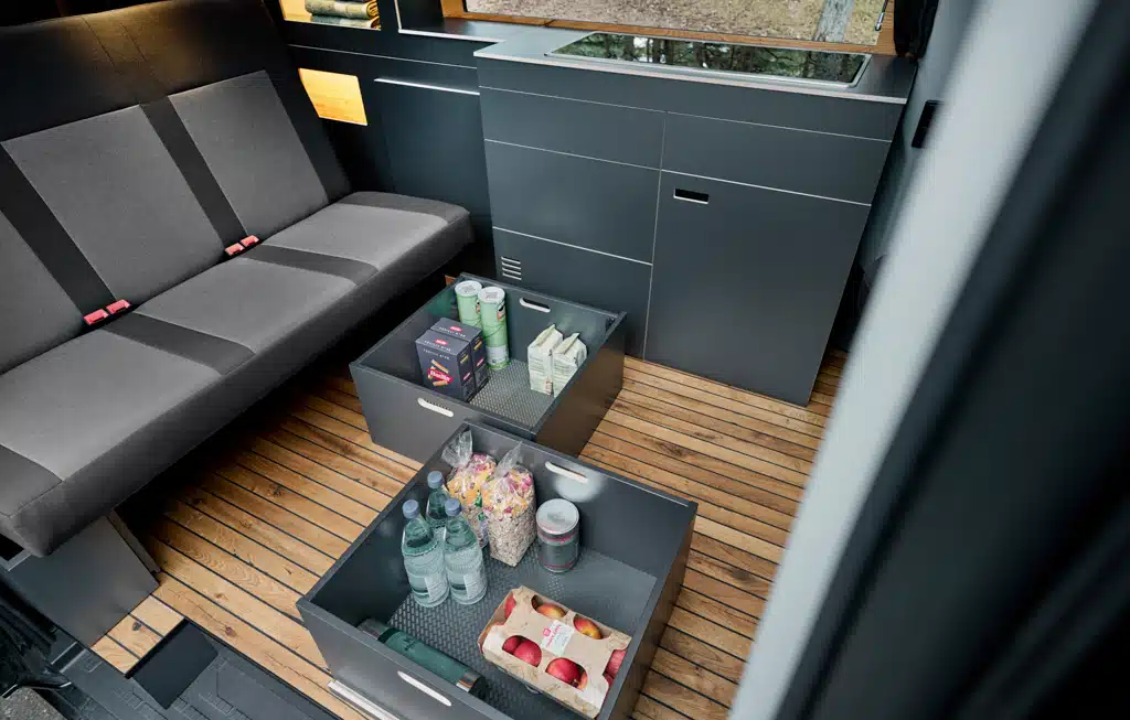 Blick auf die Dreiersitzbank mit darunterliegenden, herausnehmbaren Schubladen im Custom-Bus