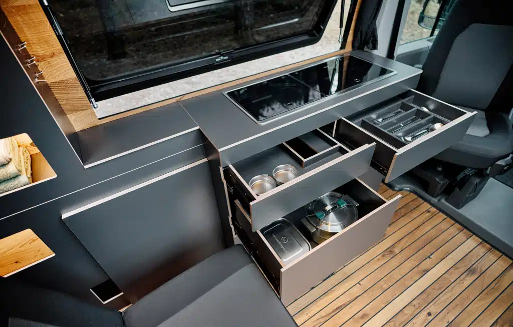 Küchenzeile mit geöffneten Schubladen im Custom-Bus Campervan