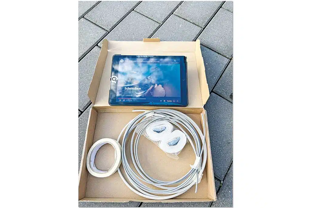 Ein Tablet, auf dem ein Video abgespielt wird, und mehrere Kabel in einem Karton