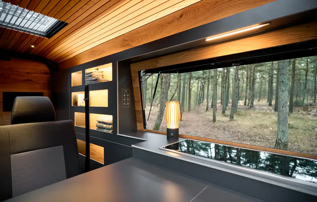 Innenraum des Custom-Bus Campervans mit Blick aus einem großen, seitlichen Panoramafester