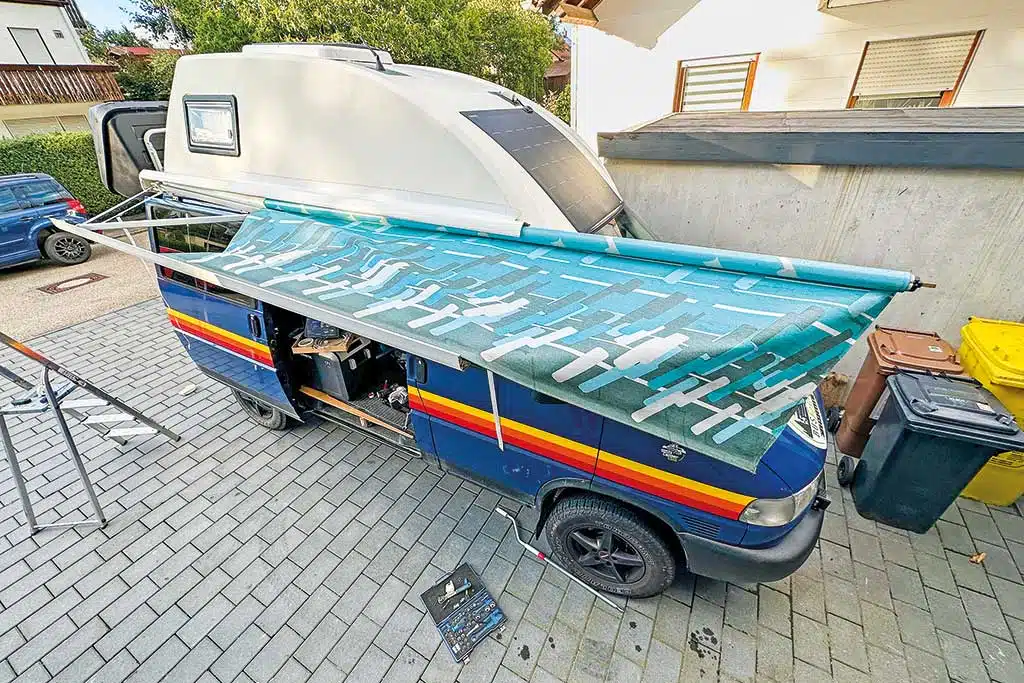 Herausziehen eines Markisentuchs aus der Markise an einem VW Bus