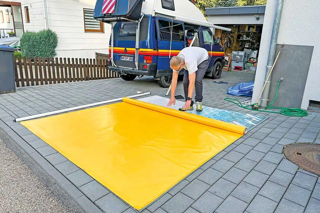 Ausgebreitetes gelbes Markisentuch vor blauem VW Bus