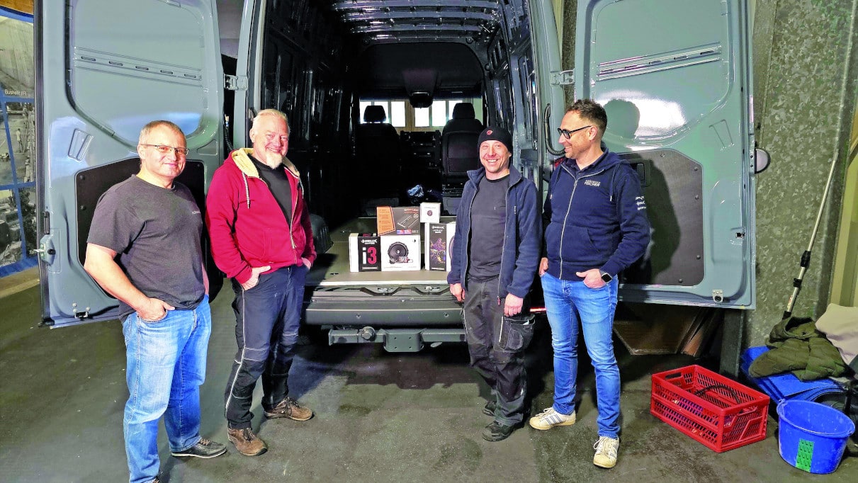 Die vier Experten von Audiotec vor der geöffneten Hecktüre des Vans.