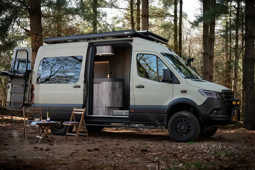 Hellbeigefarbener Allrad-Sprinter mit Campingausstattung im Wald