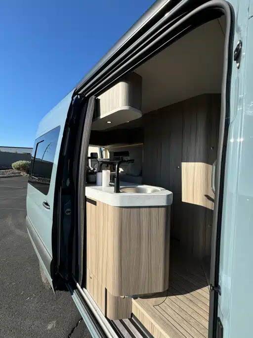 Blick auf die Campingausstattung eines Campingbusses bei geöffneter Schiebetür