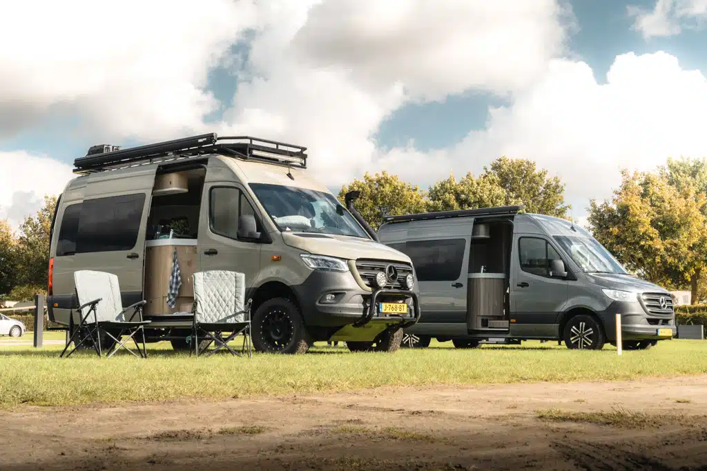 Zwei Offroad-Kastenwagen mit Campingausbau auf einer Rasenfläche nebeneinander