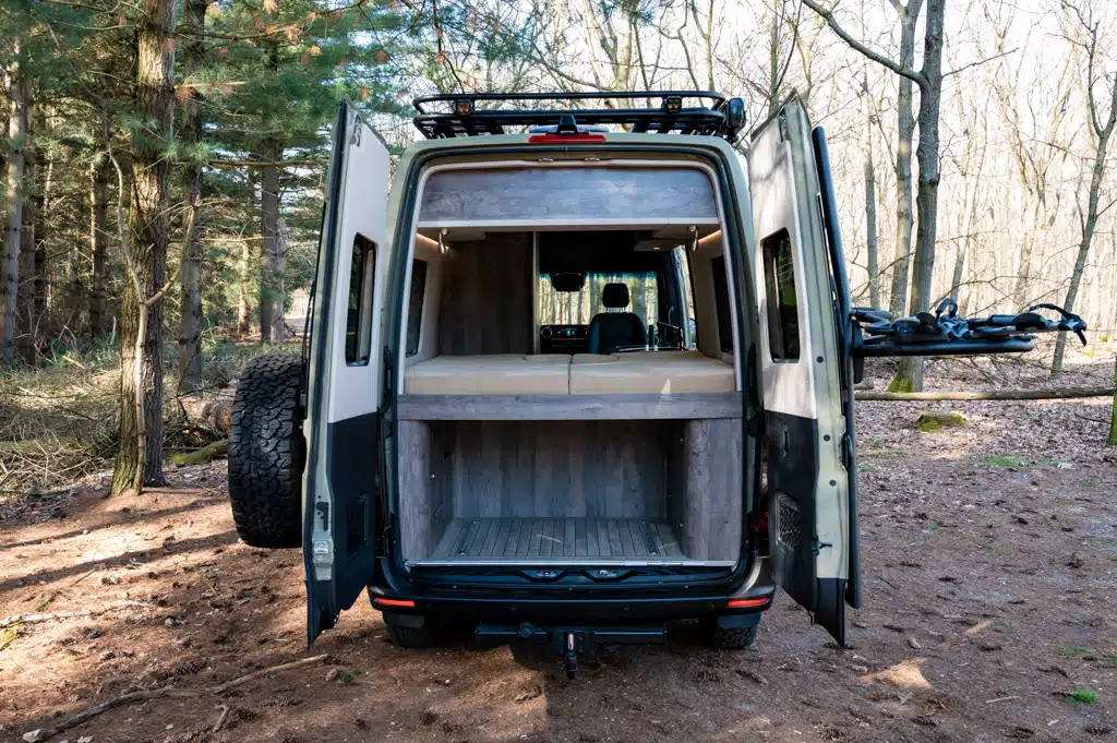 Campervan mit geöffneten Hecktüren im Wald