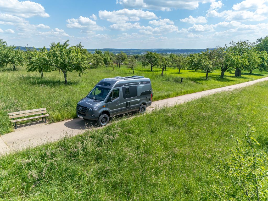 Silbergrauer Kastenwagen auf einer Landstraße in sommerlicher Landschaft