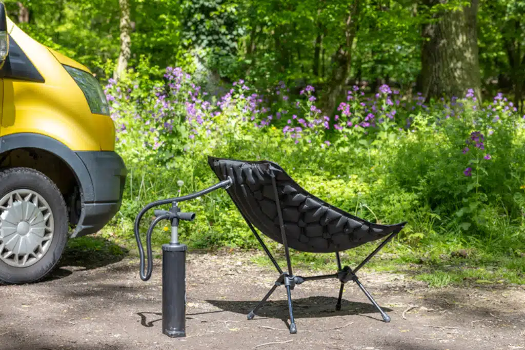 Aufgeblasener Campingstuhl auf Gestell mit Pumpe vor Van