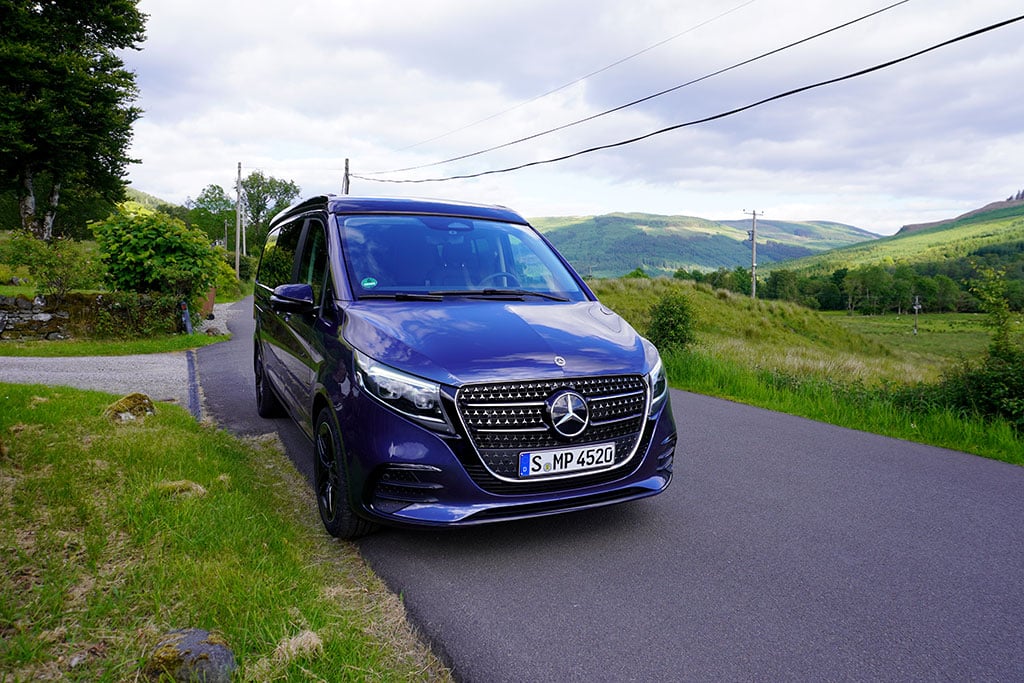 Dunkelblauer Mercedes Marco Polo auf einer Straße in hügeliger Landschaft