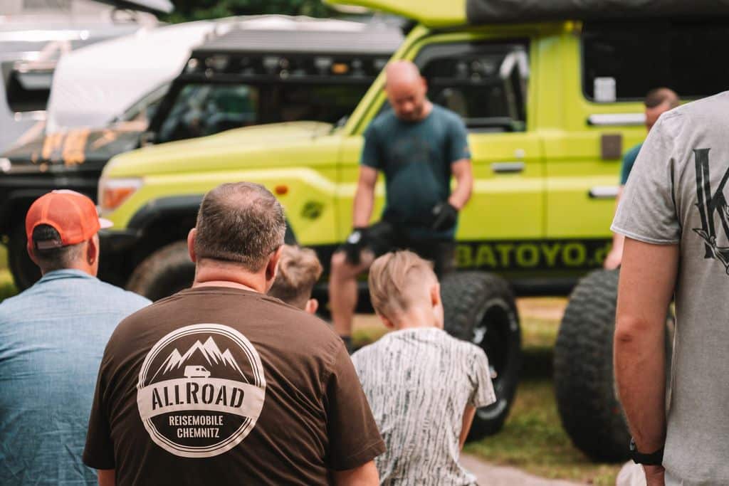 Blick auf ein paar Personen von hinten, im Hintergrund unscharf ein Fahrzeug mit Batoyo-Aufschrift