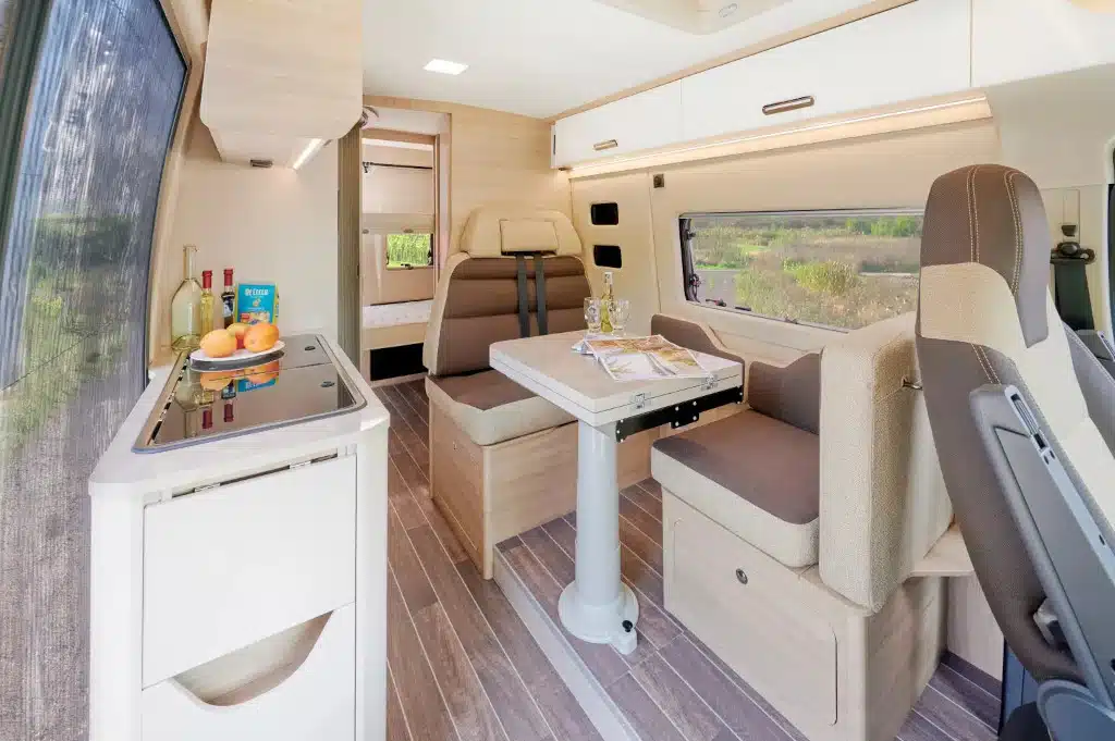Camper innen mit aufgeklapptem Tisch und Türe zum Heckbereich offen