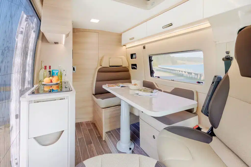 Camper Innen mit aufgeklapptem Tisch und Türe zum Heckbereich geschlossen