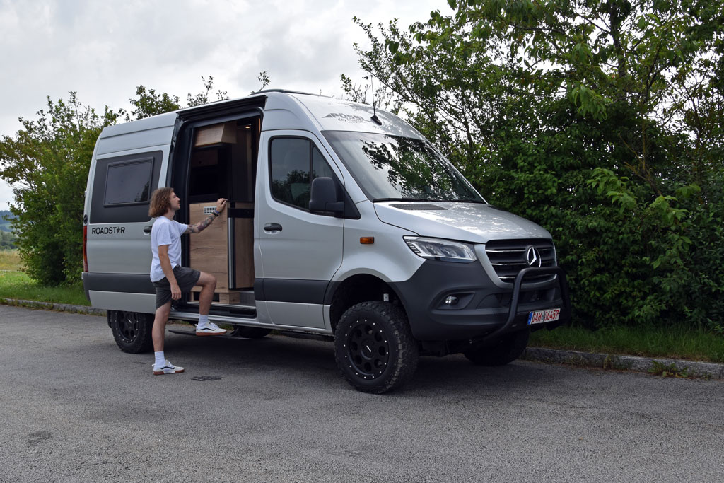 Junger Mann begutachtet Campervan auf Allrad-Sprinter von Pössl