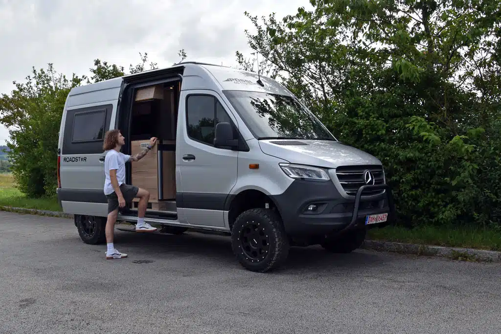 Junger Mann begutachtet Campervan auf Allrad-Sprinter von Pössl