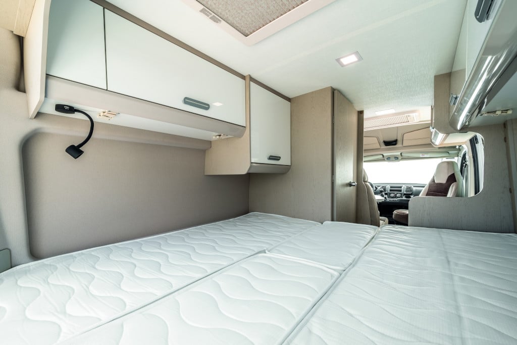 Blick von geöffneter Hecktüre auf ebene komplette Liegefläche, Hochschränke und Badschrank vor Fahrersitz