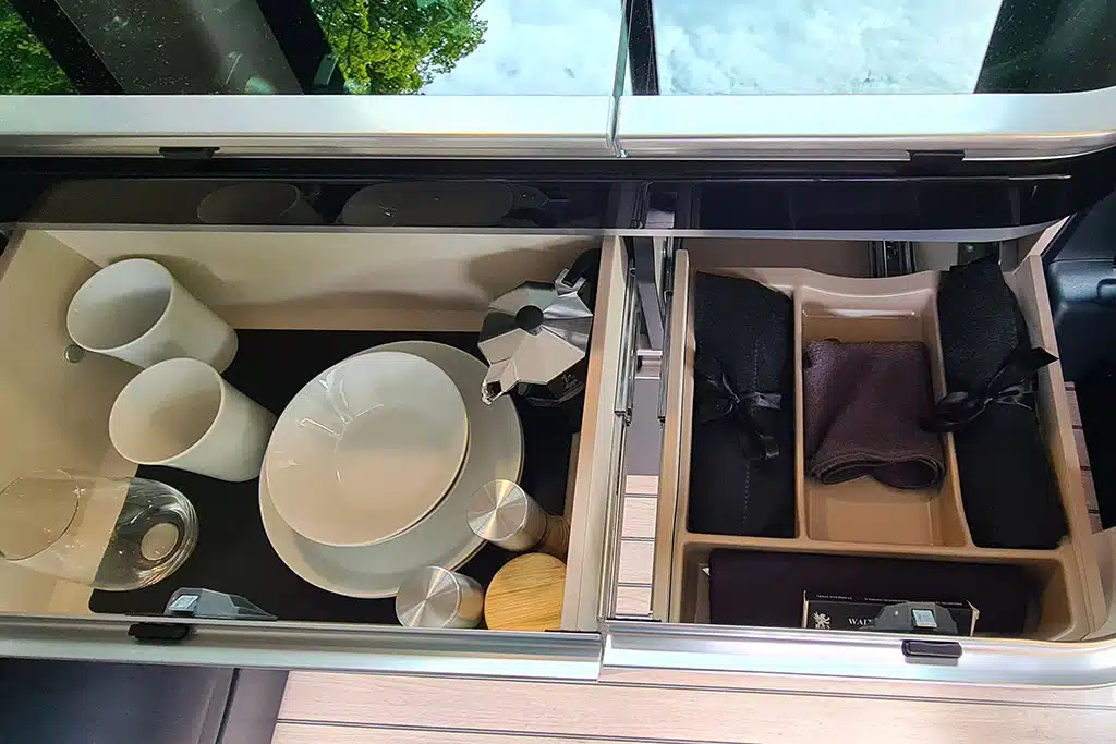 Schublade im Campervan mit Tassen, Besteck und Tellern