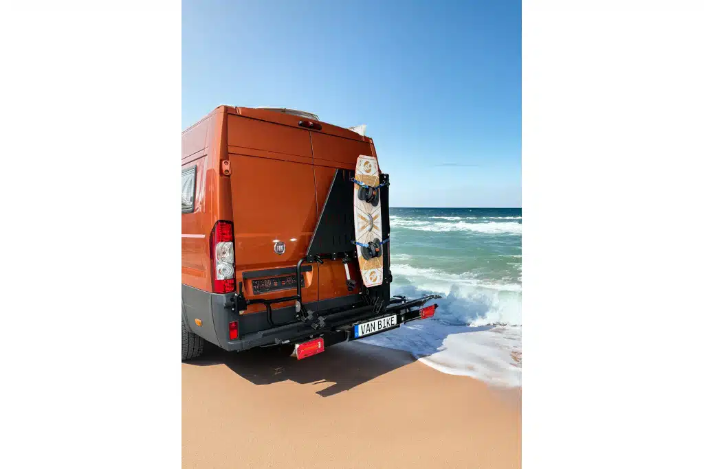 Fotomontage eines Kastenwagens am Strand mit Fahrradträger am Heck und Surfbretthalter