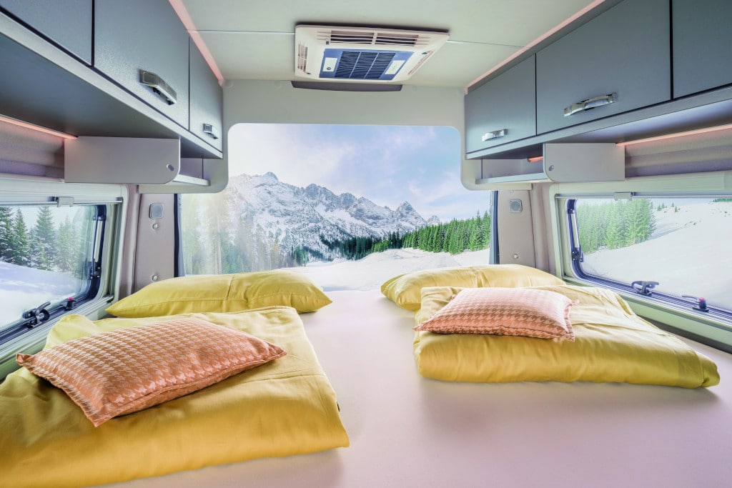 Blick nach hinten über zwei zusammengefügte Längsbetten durch geöffnete Hecktüre auf Berglandschaft